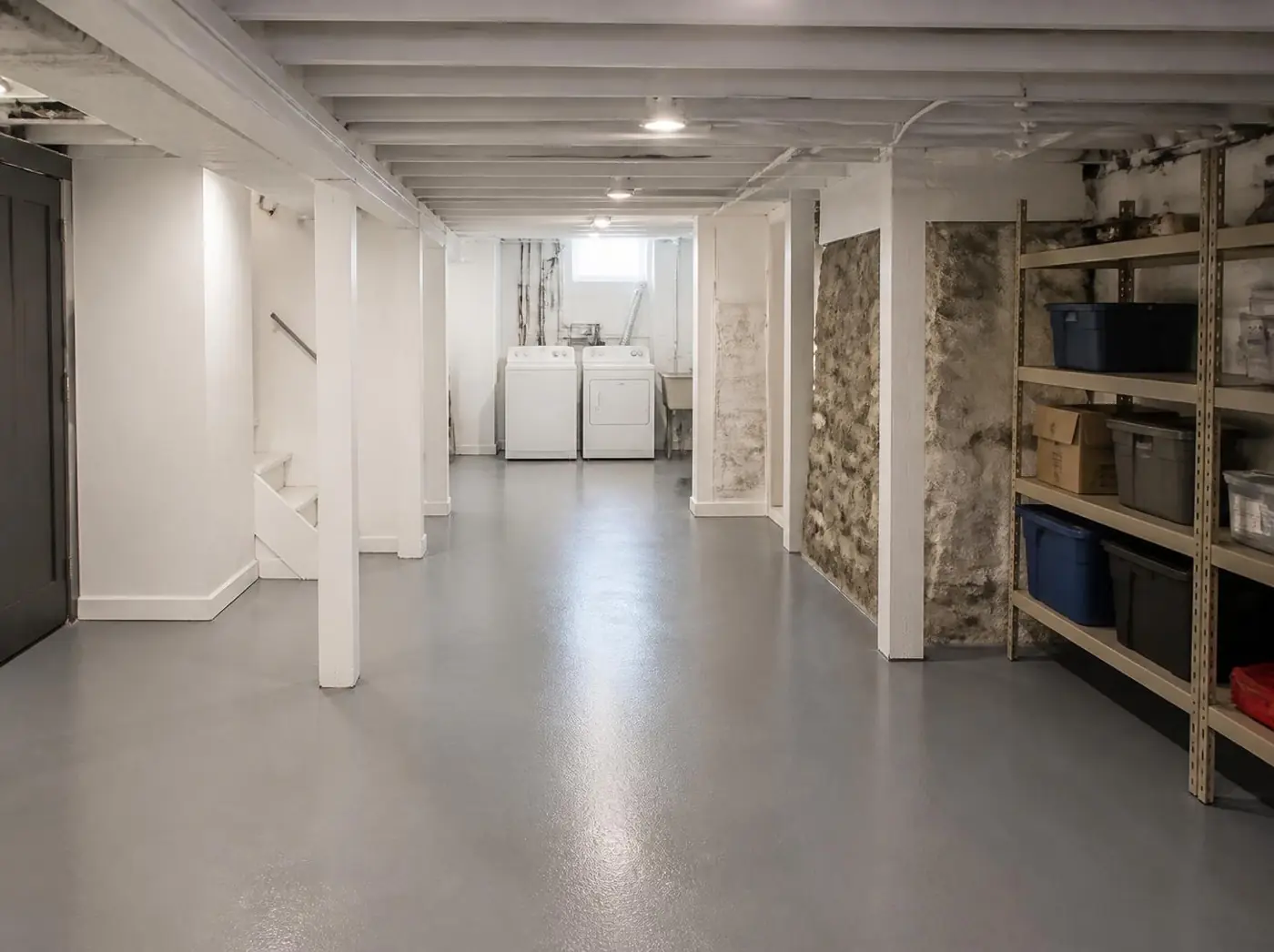 Basement with a smooth solid gray epoxy floor, laundry and storage shelves