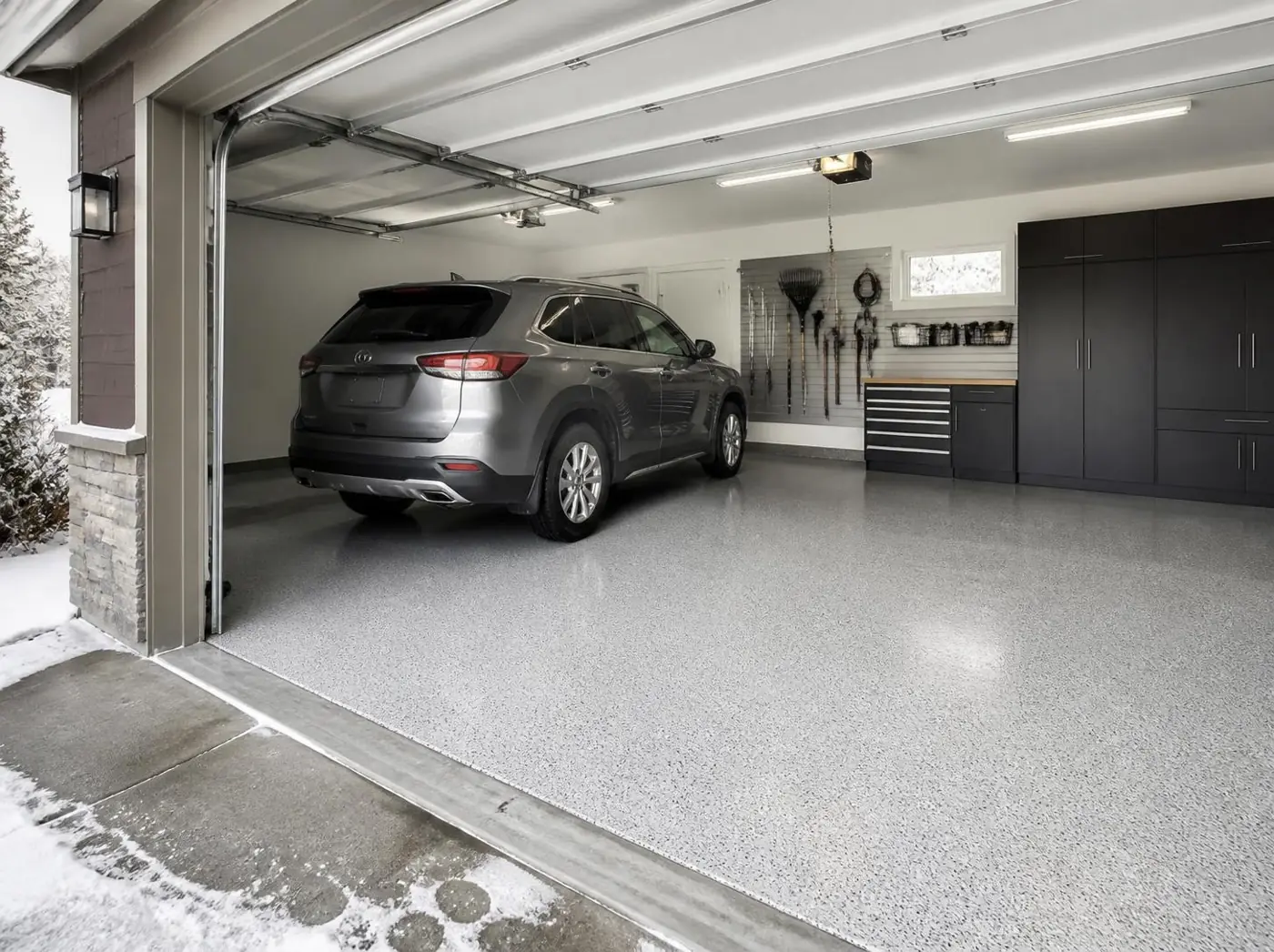 SUV parked on a light gray polyaspartic garage floor with snow on the driveway